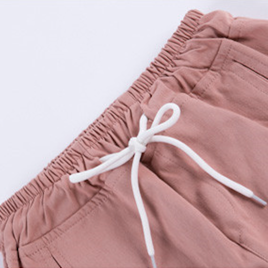 Un gros plan d'un short cargo rose pour fille, coupe droite avec resserrement aux chevilles. Ajoutez une touche de modernité à la garde-robe de votre enfant avec ce pantalon streetwear de Cargo District.