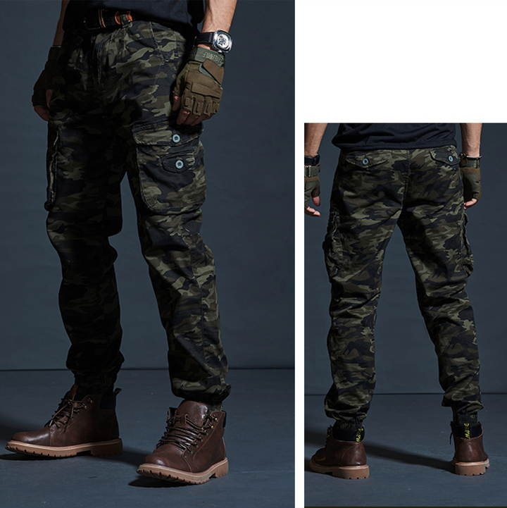 Un homme portant un pantalon cargo kaki camo avec des poches cargo latérales et des chevilles resserrées. Pantalon cargo coton resserré aux chevilles - Kaki militaire - Homme.