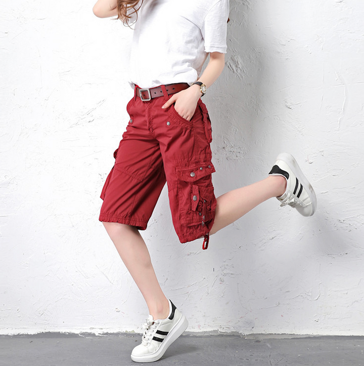 Femme portant un Short cargo long coupe droite rouge bordeaux avec poches cargo latérales. Style urbain simple et audacieux. Tailles US 28 à 38. Conçu en coton pour un confort optimal.