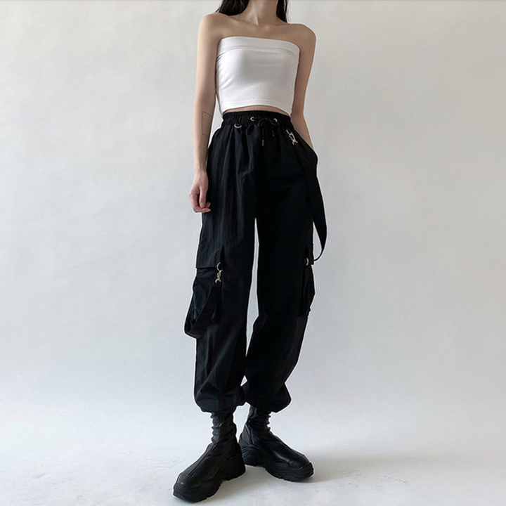 Femme portant un pantalon cargo noir avec sangles bretelles amovibles. Style audacieux et moderne pour un ajustement confortable et sûr. Disponible du S au 3XL.