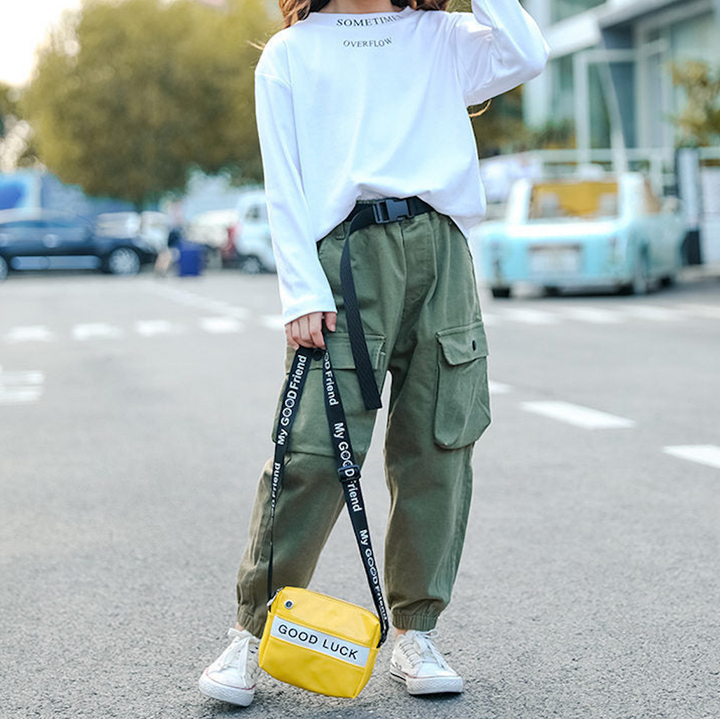 Une femme portant un pantalon blanc et une chemise verte, tenant une sangle.