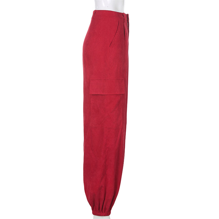 Un pantalon cargo baggy en velours côtelé rouge pour femme avec chaînes sur le côté. Taille haute, finition velours côtelé et élastique aux chevilles. Disponible du S au L.