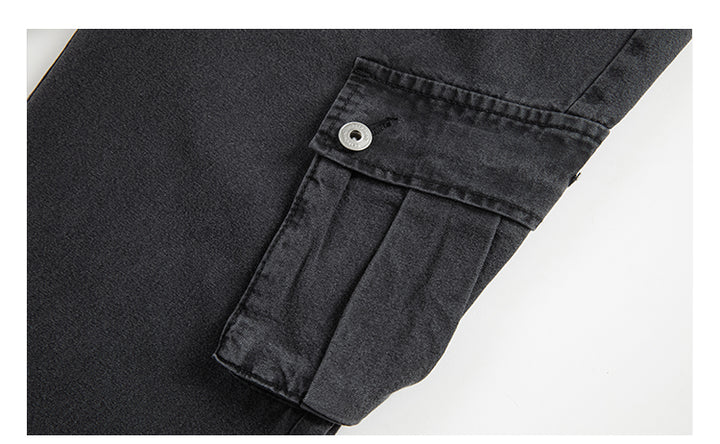 Un gros plan sur une poche d'un Jean cargo jogger coupe large noir pour homme de la marque Cargo District. La poche est inclinée et fermée par des boutons, ajoutant une touche unique à ce jean streetwear.