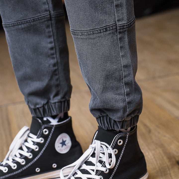 Un homme portant des chaussures noires et blanches, avec un jean cargo jogger patch gris foncé - Homme.