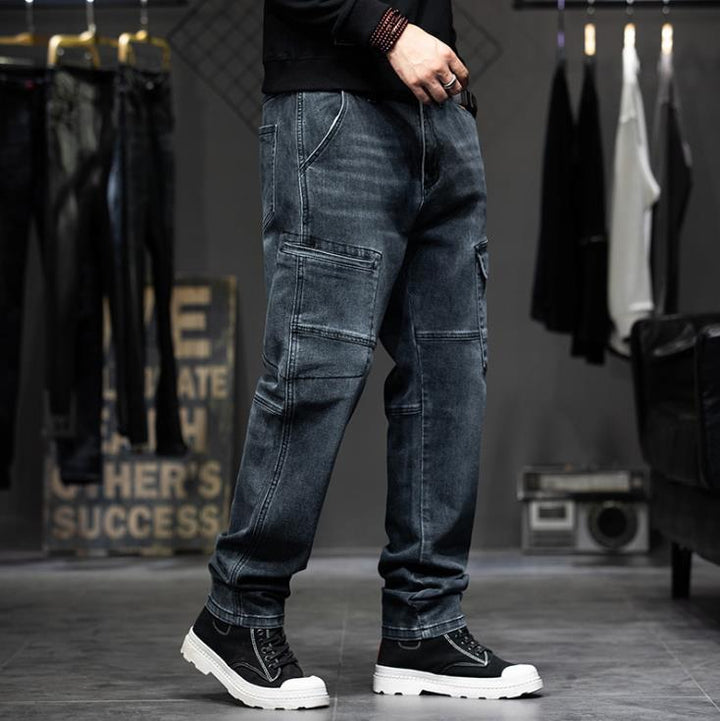 Un homme portant un jean cargo coupe droite stretch bleu avec des poches latérales à pression. Look tendance et confortable pour toutes les morphologies.