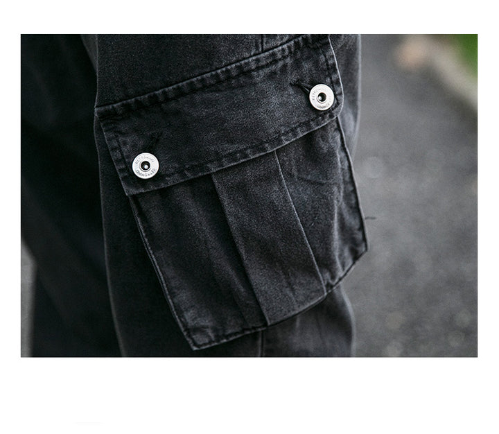 Un gros plan sur une poche boutonnée d'un Jean cargo jogger coupe large noir pour homme. Le jogger en toile denim offre confort et durabilité, avec des poches latérales inclinées. Tailles disponibles : S à 2XL. Inspiré par la tendance streetwear, ce jean est idéal pour un look décontracté.