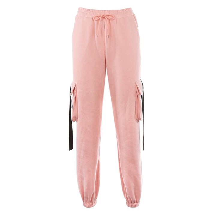 Un pantalon cargo rose avec lanières noires pour femme, coupe jogger, taille haute et élastique à la taille. Disponible du S au L.