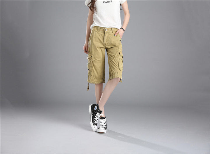 Une personne portant un short cargo long coupe droite beige et des baskets. Le short a une coupe droite et ample, avec une taille basse et des poches cargo latérales. Fabriqué en coton pour un confort optimal. Disponible en tailles US 28 à 38. Image du produit du magasin Cargo District.