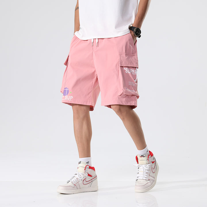 Un homme porte un short cargo rose avec des inscriptions, idéal pour un style décontracté. Coupe ample, jusqu'aux genoux, élastique à la taille. Matière légère et durable en polyester. Disponible du M au 8XL. Cargo District - Vente de vêtements de style cargo. (120 characters)