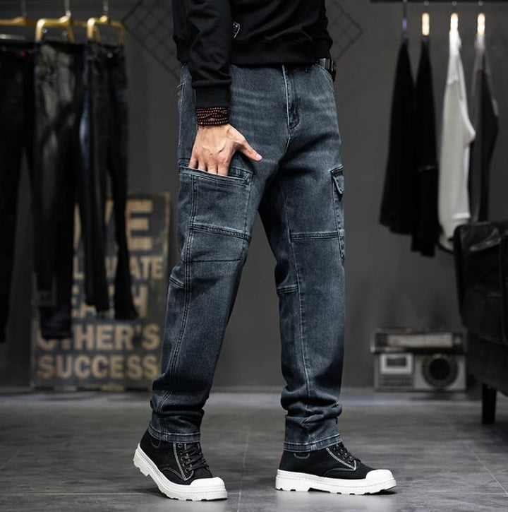 Un homme portant un jean cargo coupe droite, bleu, dans un magasin de vêtements de style cargo. Le jean est légèrement délavé avec des poches latérales à pression pour une touche pratique. Disponible du 28 au 44, il assure un confort optimal grâce à sa matière extensible en toile denim.