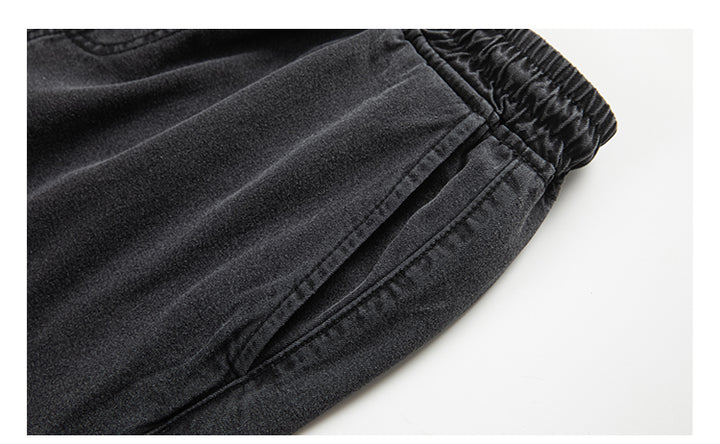 Un gros plan sur un pantalon noir cargo jogger coupe large pour homme. Confortable et tendance, ce pantalon en toile denim garantit durabilité et style décontracté. Tailles disponibles : S à 2XL. Poches latérales inclinées fermées par des boutons ajoutant une touche unique.