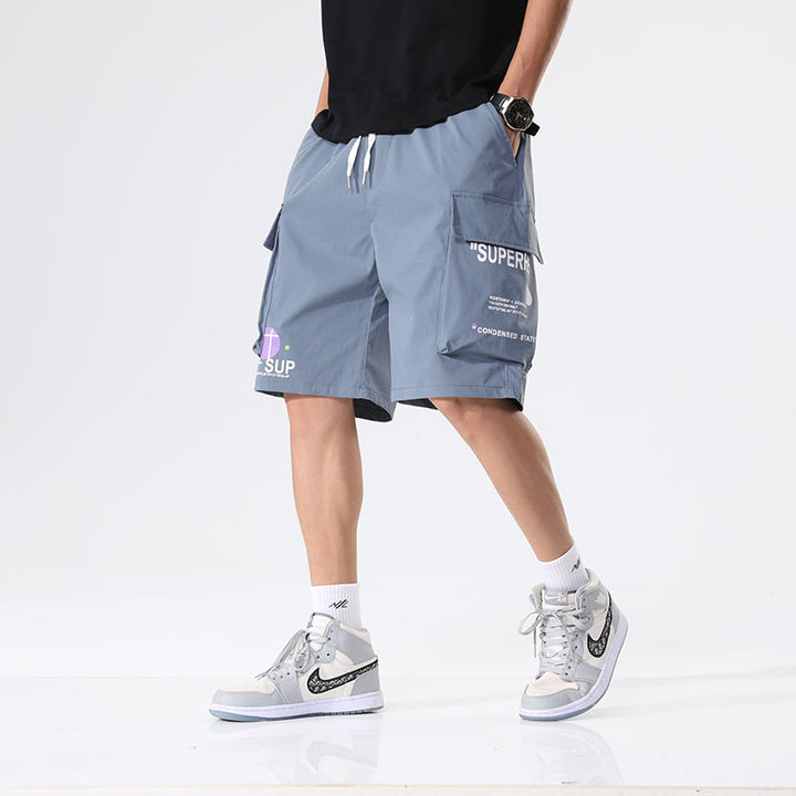 Un homme portant un short cargo ample léger avec inscriptions, couleur bleue. Parfait pour un style décontracté. Disponible en différentes tailles.