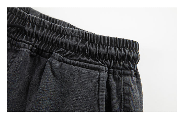 Un gros plan sur un pantalon cargo jogger coupe large noir pour homme. Confortable et tendance, ce pantalon en toile denim garantit durabilité et style décontracté. Tailles disponibles : S à 2XL. Poches latérales inclinées fermées par des boutons ajoutant une touche unique.