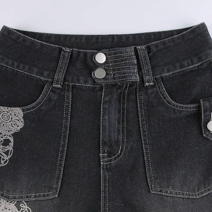 Un gros plan sur un jean cargo baggy gris avec des motifs de rosaces blanches. Ce jean taille basse et coupe baggy offre un look décontracté et stylé. Les poches cargo latérales ajoutent une touche de fonctionnalité. Disponible du S au L.