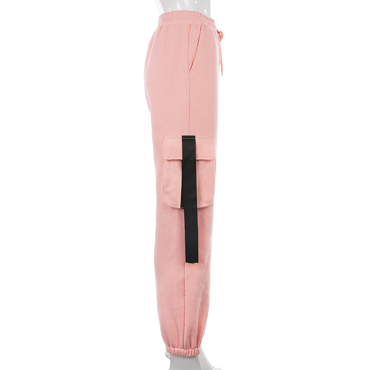 Un pantalon cargo rose avec lanières noires pour femme, taille haute et coupe jogger. Parfait pour un look urbain et féminin. Disponible du S au L.