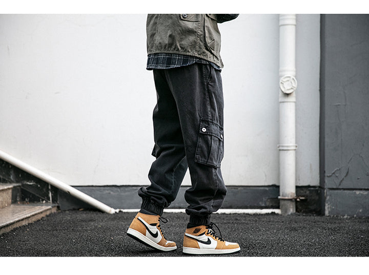 Un homme porte des chaussures marron et blanches avec un pantalon noir. Jean cargo jogger coupe large - Noir - Homme.