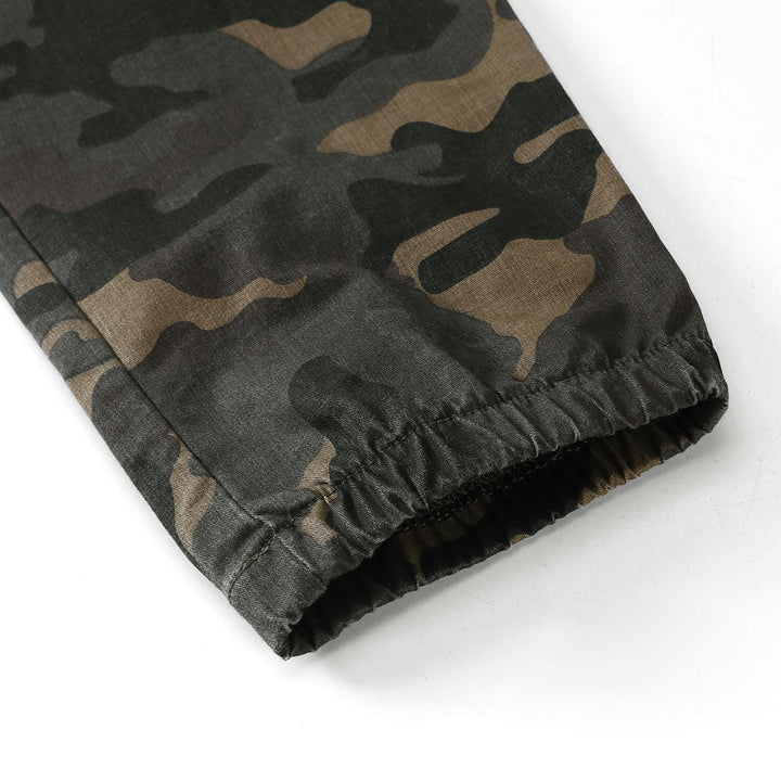 Un pantalon cargo jogger vert militaire pour garçon avec motif camouflage et coutures apparentes. Tailles disponibles de 7-8 ans (130 cm) à 14-15 ans (170 cm). Confortable avec taille élastique et poches latérales.