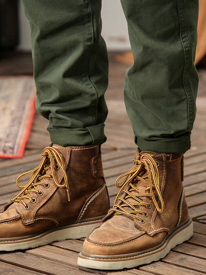 Un homme portant des bottes marron avec lacets jaunes, pantalon cargo coupe droite kaki pour un look masculin intemporel. Poches cargo sur les côtés se fermant par bouton, confortable et stylé. Tailles US 28 à 38.