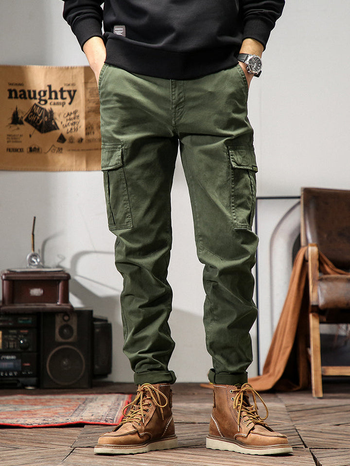 Un homme portant un pantalon cargo kaki avec des poches cargo sur les côtés. Coupe droite pour un look masculin intemporel. Disponible en tailles US 28 à 38. Confortable et stylé.