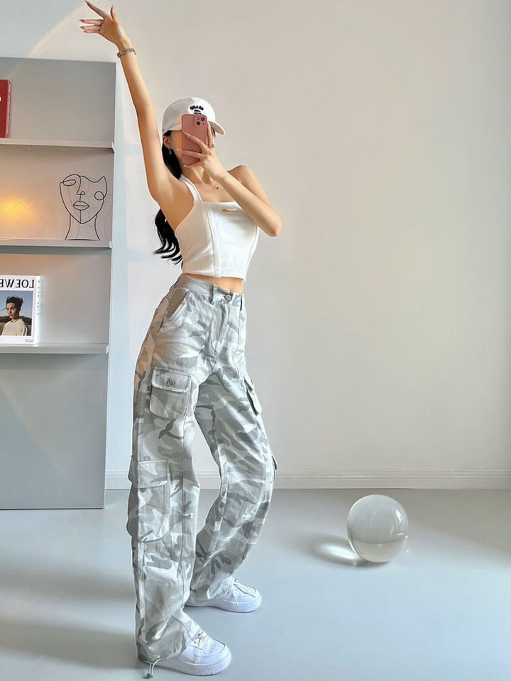 Une femme prenant un selfie avec un pantalon cargo taille haute jambes larges gris camo. Un look urbain unique et tendance avec des poches pratiques et une taille élastique au dos pour un ajustement parfait. Disponible du M au 3XL.