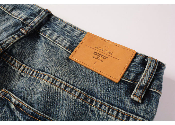 Un gros plan sur l'étiquette en cuir d'un jean bleu cargo délavé pour homme. Les petites poches latérales ajoutent une touche tendance à ce jean coupe droite. Disponible en tailles US 28 à 40. Confectionné en 100% coton pour un confort durable. Parfait pour une tenue décontractée et tendance.