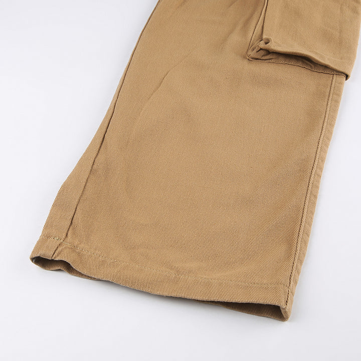 Un gros plan sur un pantalon cargo baggy camel pour femme avec des lanières aux poches. Un jean tendance, confortable et taille haute, idéal pour un look urbain. Disponible en tailles S à L.