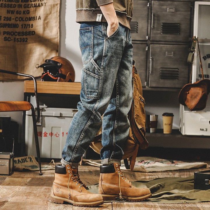 Un homme debout devant un casier, portant un jean cargo délavé coupe droite - Bleu. Les détails du jean comprennent de petites poches latérales, offrant une touche tendance. Disponible en tailles US 28-40, en 100% coton pour un confort durable. Parfait pour une tenue décontractée et tendance.