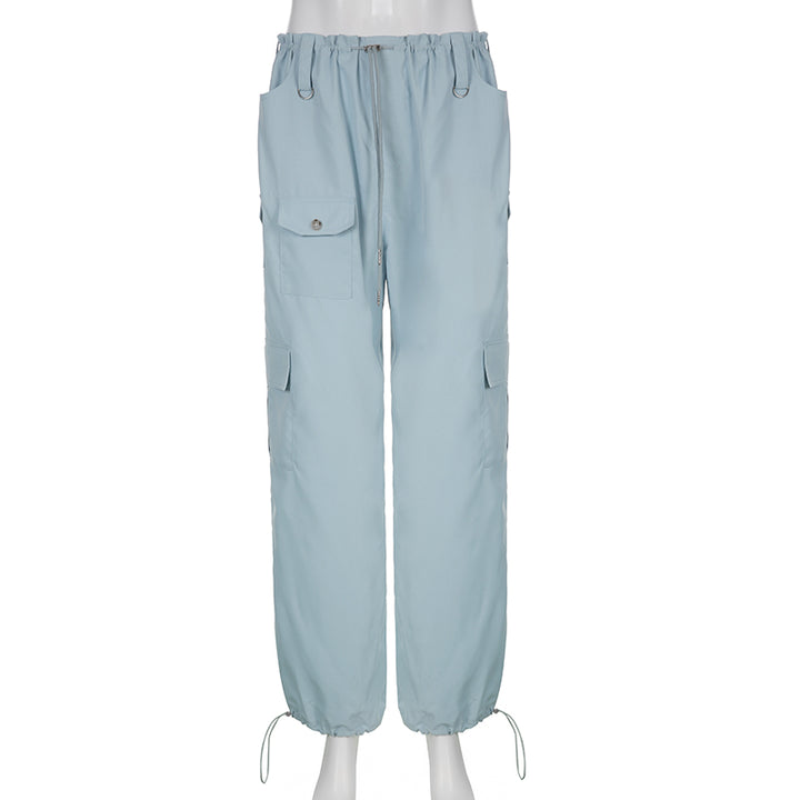 Un mannequin porte un pantalon cargo baggy taille basse élastique en polyester et spandex bleu ciel. Le pantalon a des poches et un élastique aux chevilles pour un look tendance. Disponible en tailles S à L.