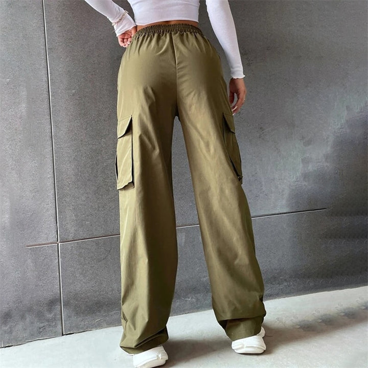 Une personne porte un pantalon cargo baggy kaki pour femme avec taille haute et jambes larges. Le pantalon est confortable et pratique avec ses multiples poches sur les jambes. Disponible du S au XL.