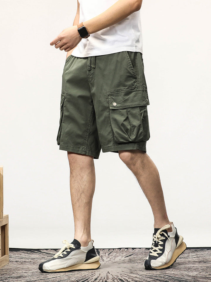 Un homme portant un short cargo kaki avec une montre et des baskets.