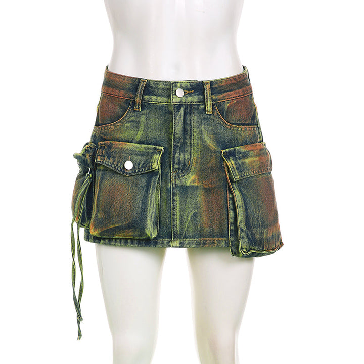 Une mannequin porte une jupe cargo en jean bleu vert avec plusieurs poches. La jupe a une coupe droite et offre un look urbain tendance. Disponible en tailles S à L.