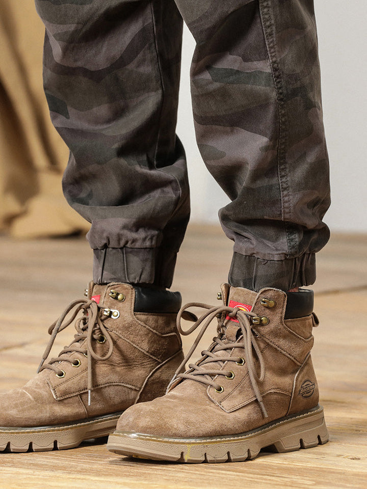 Un homme portant des bottes marron, un pantalon cargo coupe large resserré aux chevilles de couleur gris militaire. Un look masculin et militaire avec un confort optimal en coton. Tailles disponibles: 28 à 38.