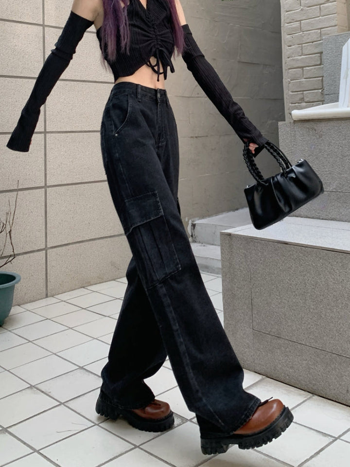 Une femme portant un jean cargo noir taille haute, avec un haut noir. Le jean a une coupe large et des poches cargo latérales, ajoutant une touche fonctionnelle. Disponible en tailles S à XL.