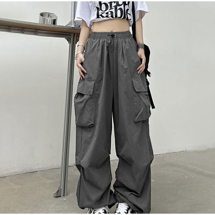 Une personne porte un Pantalon cargo baggy léger gris avec des poches latérales. Coupe confortable avec taille élastique et chevilles resserrées. Disponible du S au 3XL.