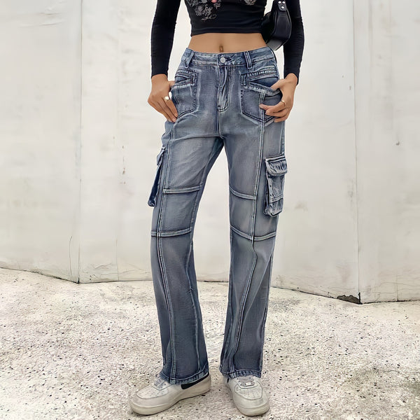 Une femme pose dans la rue avec un top manches longues noir court, des baskets blanches et un sac noir. Il porte un jean cargo taille haute vintage bleu. 