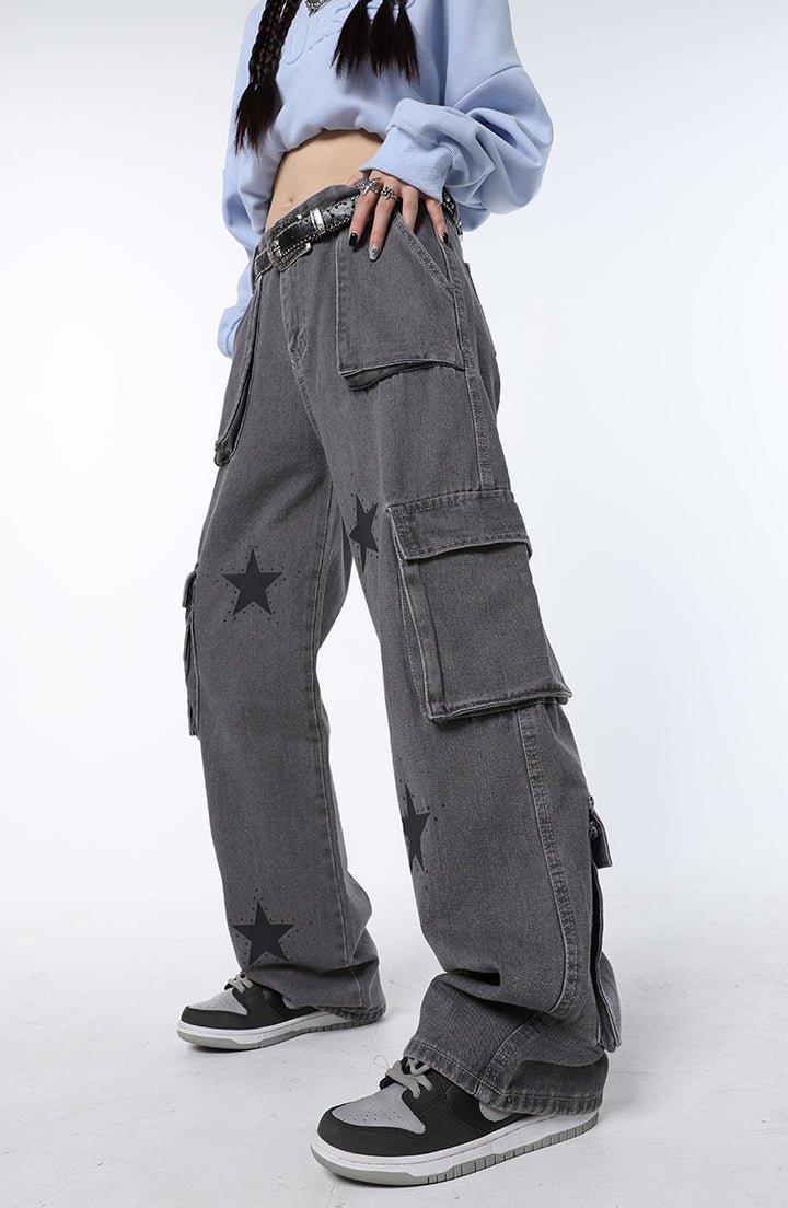 Une personne portant un jean cargo baggy gris avec des étoiles noires.