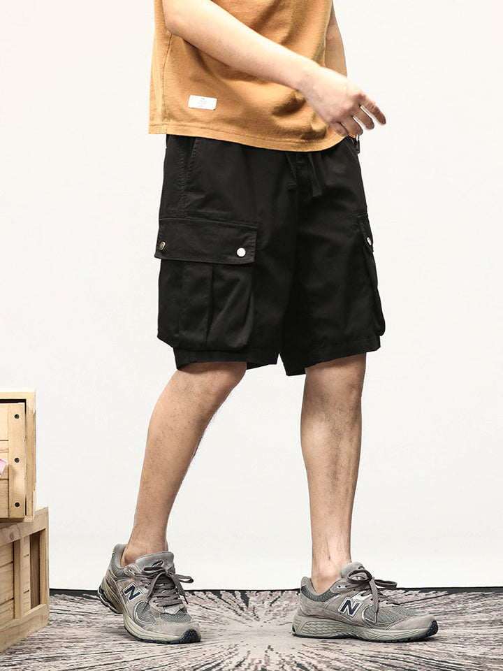 Un homme portant un short cargo noir avec des sneakers.