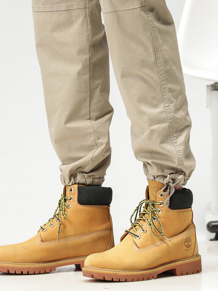 Un homme portant un pantalon cargo ample coupe droite beige avec des bottes jaunes.