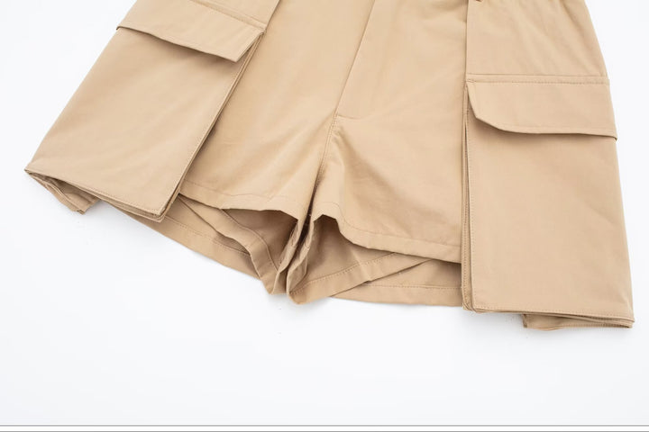 Un gros plan sur une paire de shorts cargo beige pour femme avec des poches cargo dépassant légèrement de la jupe. Jupe short cargo - Beige - Femme.