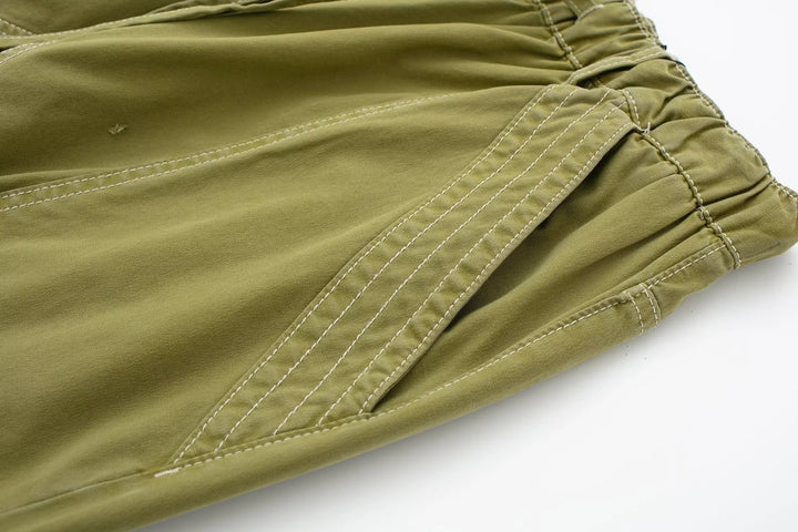 Un pantalon cargo vert avec coutures blanches, jambe large pour une allure urbaine féminine. Taille ajustable. Disponible du XS au L.