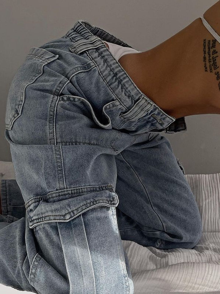 Une femme portant un jean cargo baggy bleu clair, tendance des années 90. Ce jean ajustable à la taille est fait d'un mélange de coton et de spandex pour un confort optimal. Disponible du S au L.