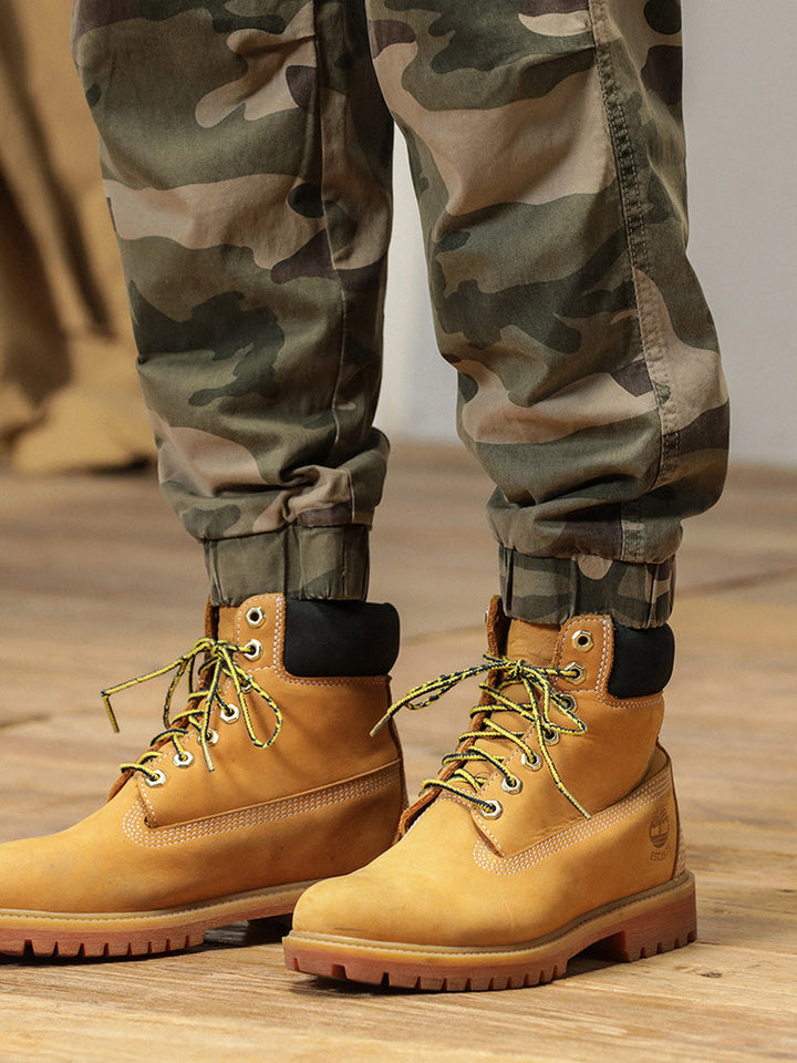 Un homme portant des bottes jaunes et un pantalon camouflage, un style militaire moderne.