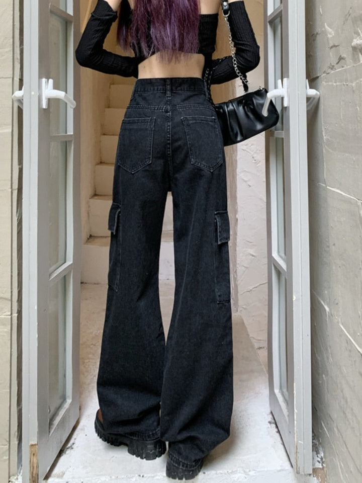 Une femme portant un jean cargo large taille haute noir avec des poches cargo latérales. Le jean est disponible du S au XL et est fabriqué en denim et en polyester. Parfait pour un style urbain tendance.
