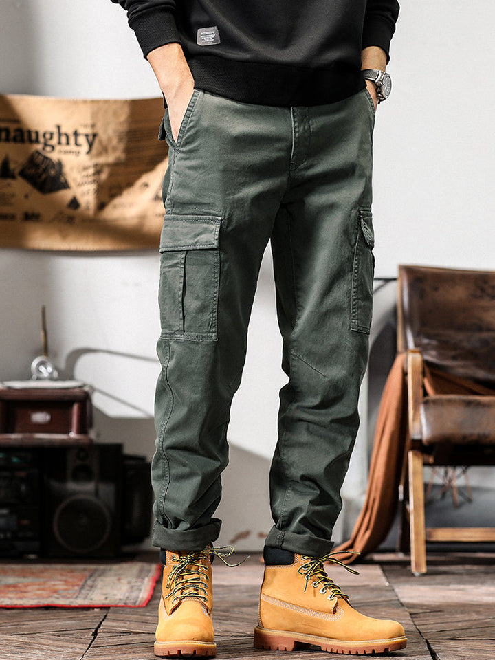 Un homme portant un pantalon cargo gris avec des poches cargo et une coupe droite. Parfait pour un look masculin intemporel et confortable. Disponible en tailles US 28 à 38.