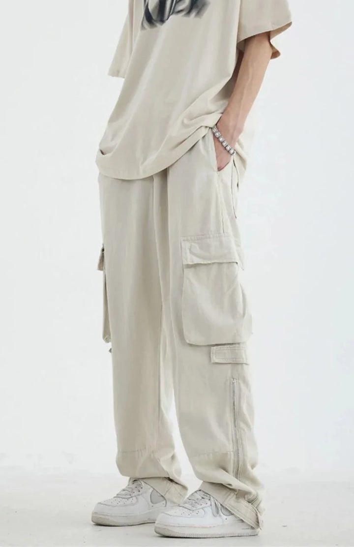 Un homme portant un pantalon blanc cargo avec poches, en coton 100%. Tailles disponibles: M à 2XL. Style décontracté, inspiré du streetwear japonais vintage.