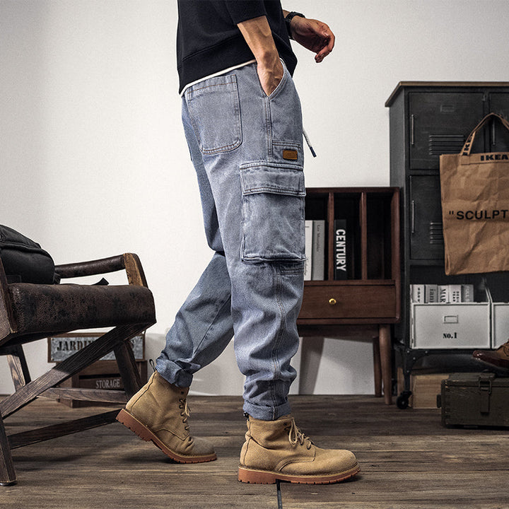 Un homme marchant dans une pièce avec un jean cargo coupe large bleu clair pour un look street décontracté. Les poches latérales cargo ajoutent une touche fonctionnelle et tendance. Disponible du XS au 5XL.