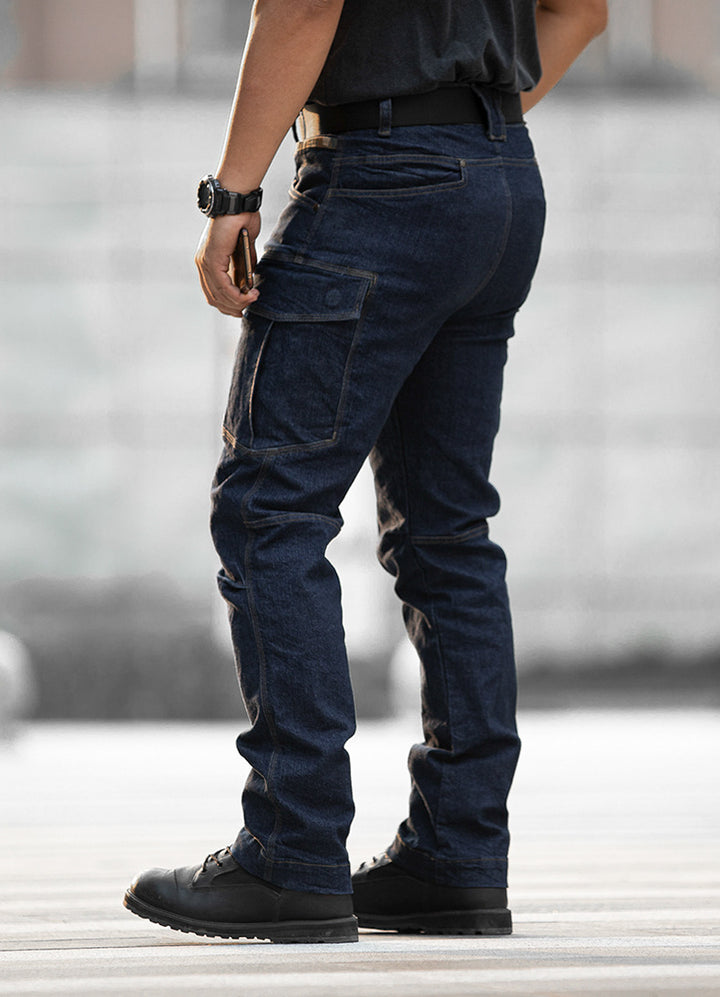 Un homme porte un jean cargo ajusté coupe droite, couleur bleu. Le jean en toile denim stretch offre un confort optimal et une grande liberté de mouvement. Doté de nombreuses poches, ce jean allie fonctionnalité et style.