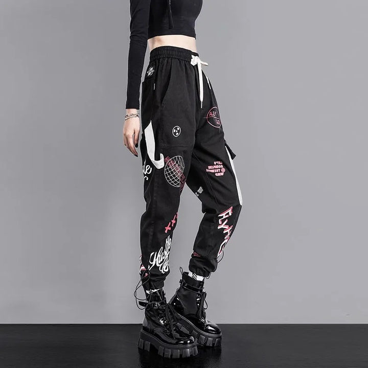 Une personne portant un pantalon cargo jogger noir à motif avec des designs blancs et roses.