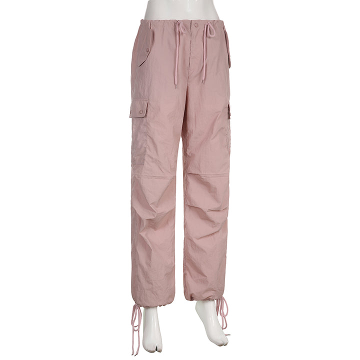 Un mannequin porte un pantalon cargo rose, taille basse et large, avec une jambe élastiquée à la cheville. Le pantalon est disponible en tailles S à L et est fait de polyester et de spandex. Ce vêtement féminin de style cargo offre une allure urbaine et décontractée.