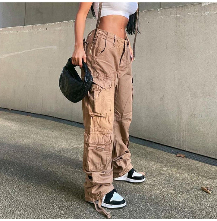 Une personne portant un haut blanc et un pantalon kaki avec une main tenant un sac à main noir. Pantalon cargo coupe droite multipoches - Camel - Femme.